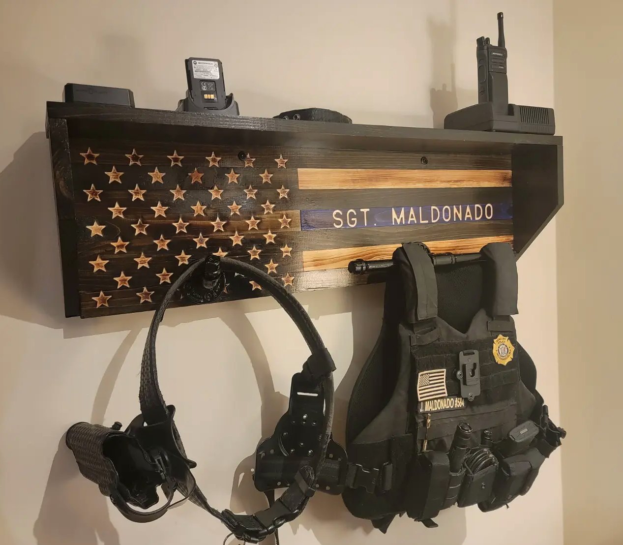 Police gear rack on a wall holding radios, a duty belt and a vest