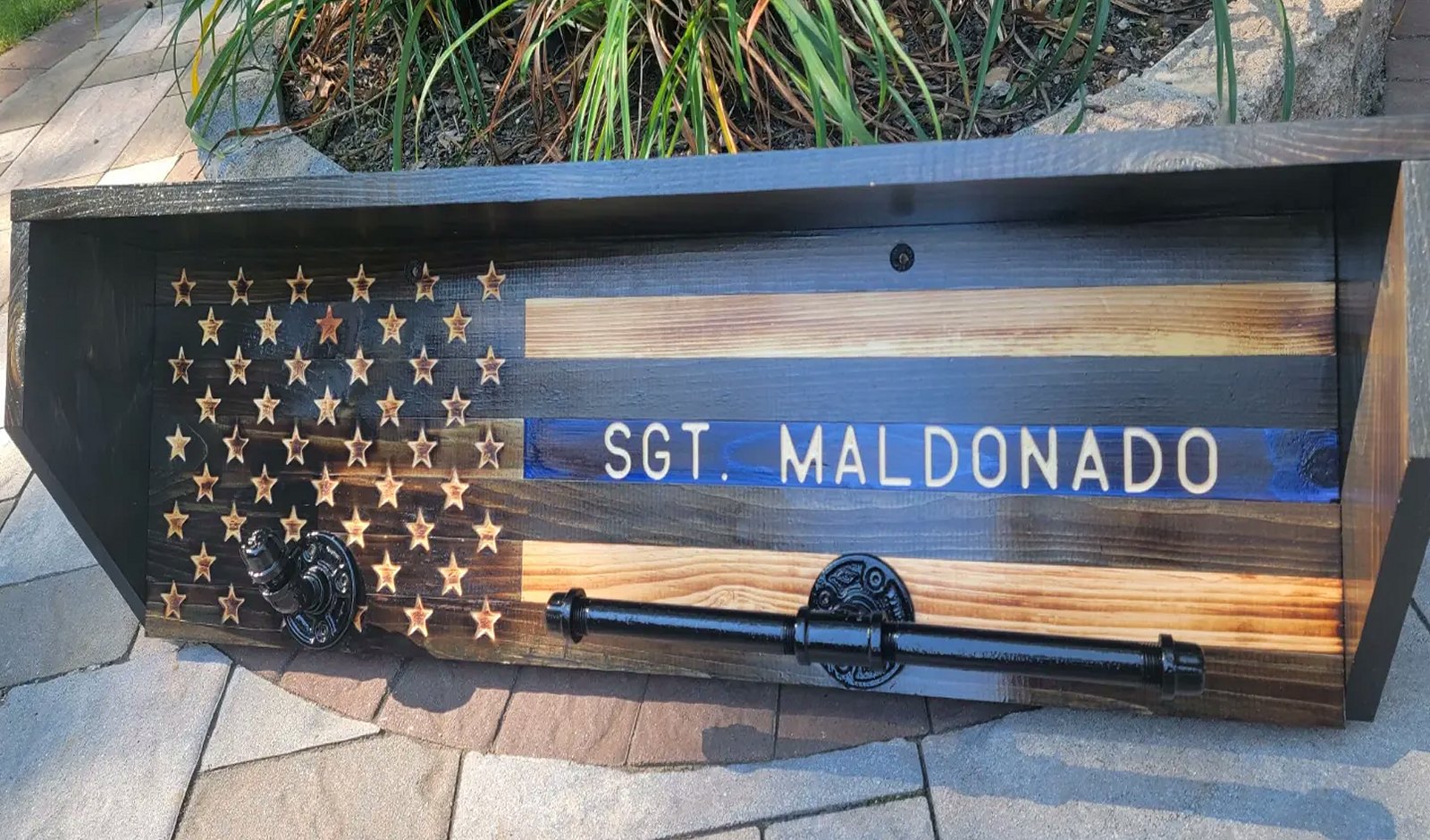 Police gear rack with a burned-wood thin blue line flag back panel engraved SGT. MALDONADO